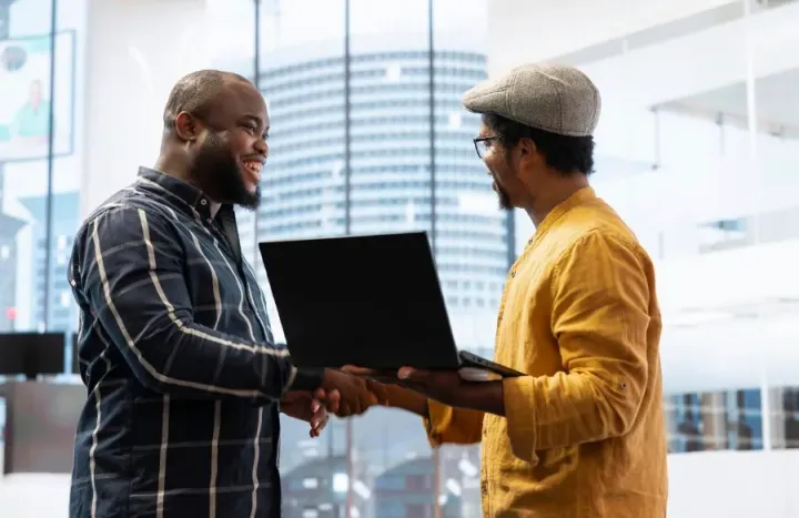 A handover handshake over a laptop in an office