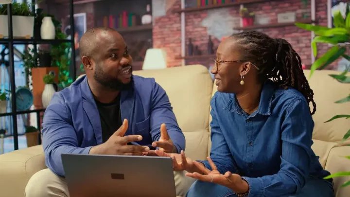Two colleagues talking through a process over a laptop