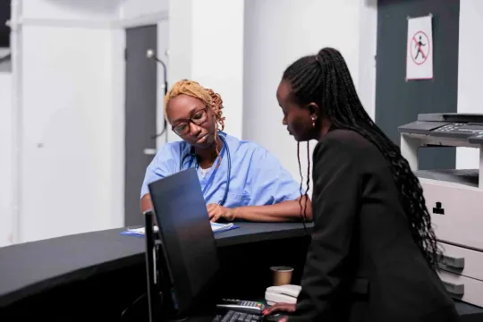 A nurse and an administrator reviewing records at a clinic desk